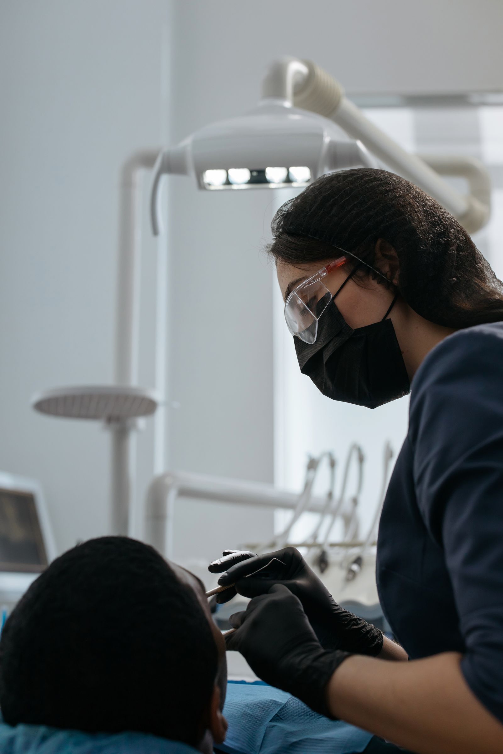 A dentist working over a patient in the operatory, close focus